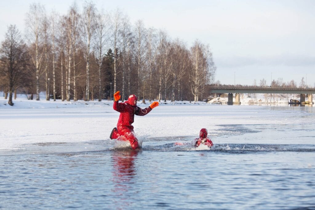 People floating in icy water wearing dry suits on the Vuoksi River in winter.