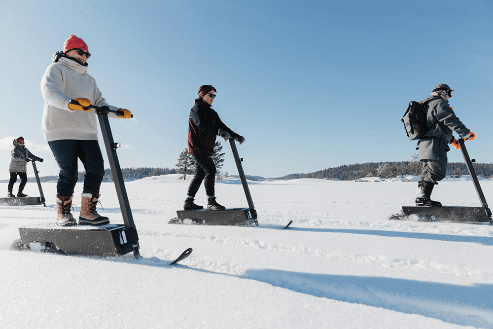Ihmisiä ajamassa Saimaan jäällä sähköisillä scooteilla